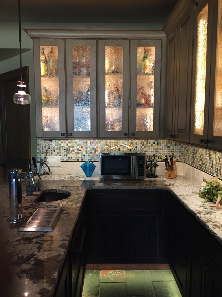 Mid-sized transitional l-shaped slate floor seated home bar photo in Denver with an undermount sink, glass-front cabinets, medium tone wood cabinets, granite countertops, multicolored backsplash, mosaic tile backsplash and multicolored countertops