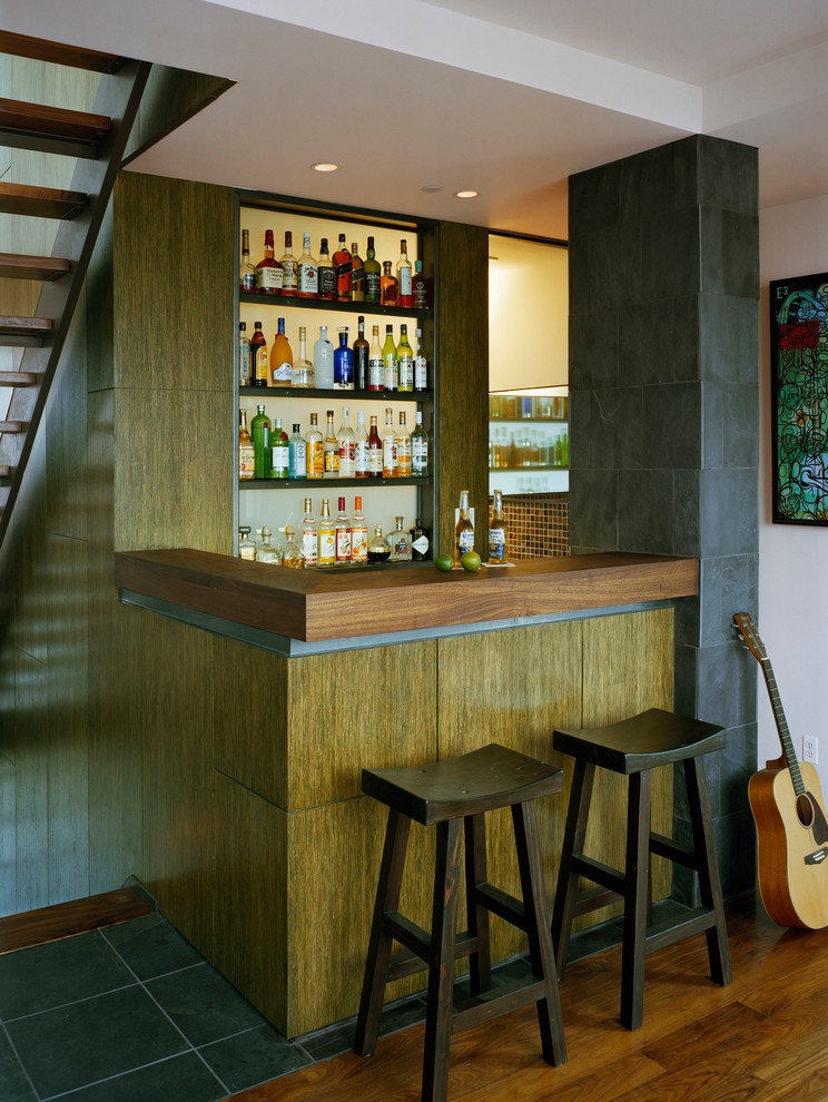 Diseño de bar en casa con barra de bar actual con armarios con paneles lisos, encimera de madera, salpicadero blanco, salpicadero de vidrio templado, suelo de madera oscura, encimeras marrones y puertas de armario de madera oscura