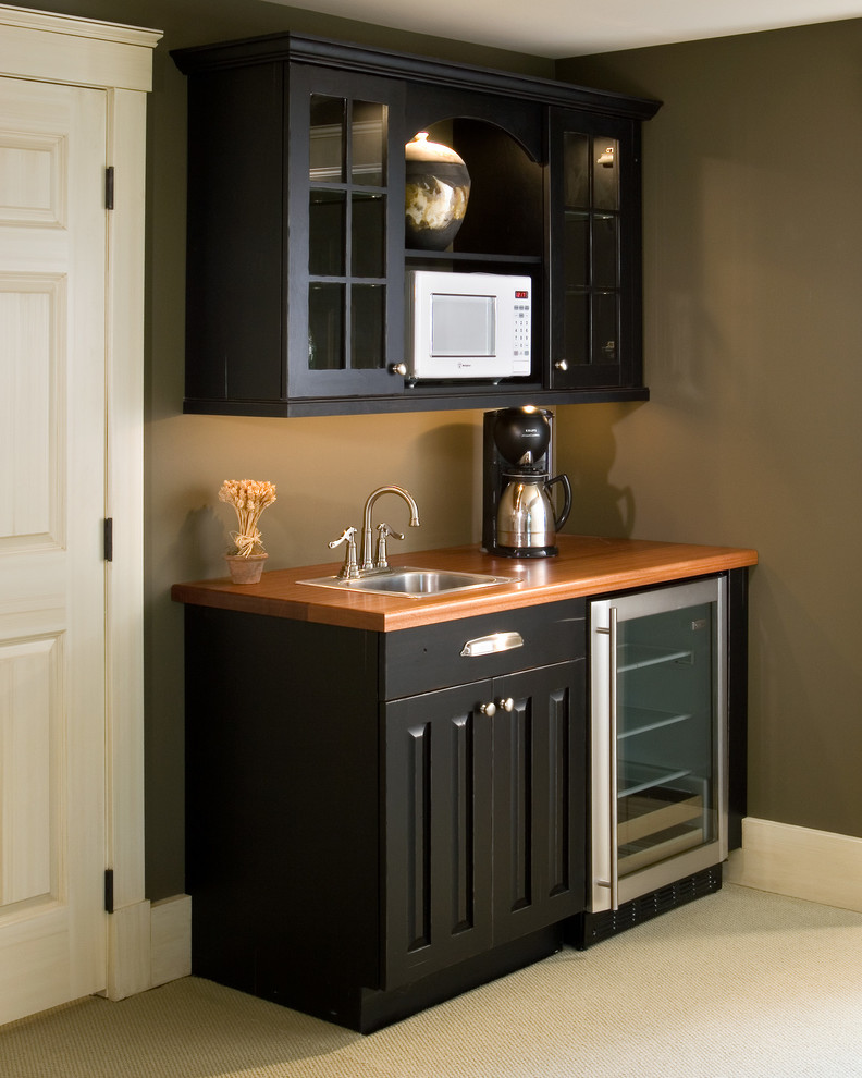 This is an example of a small classic single-wall wet bar in Boston with a built-in sink, recessed-panel cabinets, black cabinets, wood worktops and carpet.