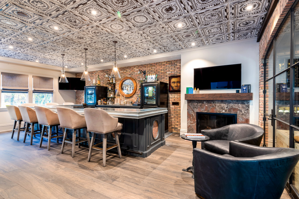 Cette image montre un bar de salon en U avec un plan de travail en zinc, une crédence en brique, des portes de placard noires, une crédence rouge, un sol en bois brun, un sol marron et un plan de travail gris.