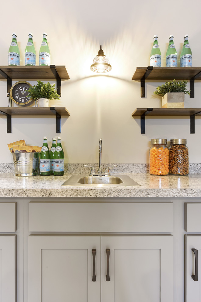 Example of a transitional wet bar design in Minneapolis with a drop-in sink, recessed-panel cabinets, gray cabinets, laminate countertops, gray backsplash and multicolored countertops