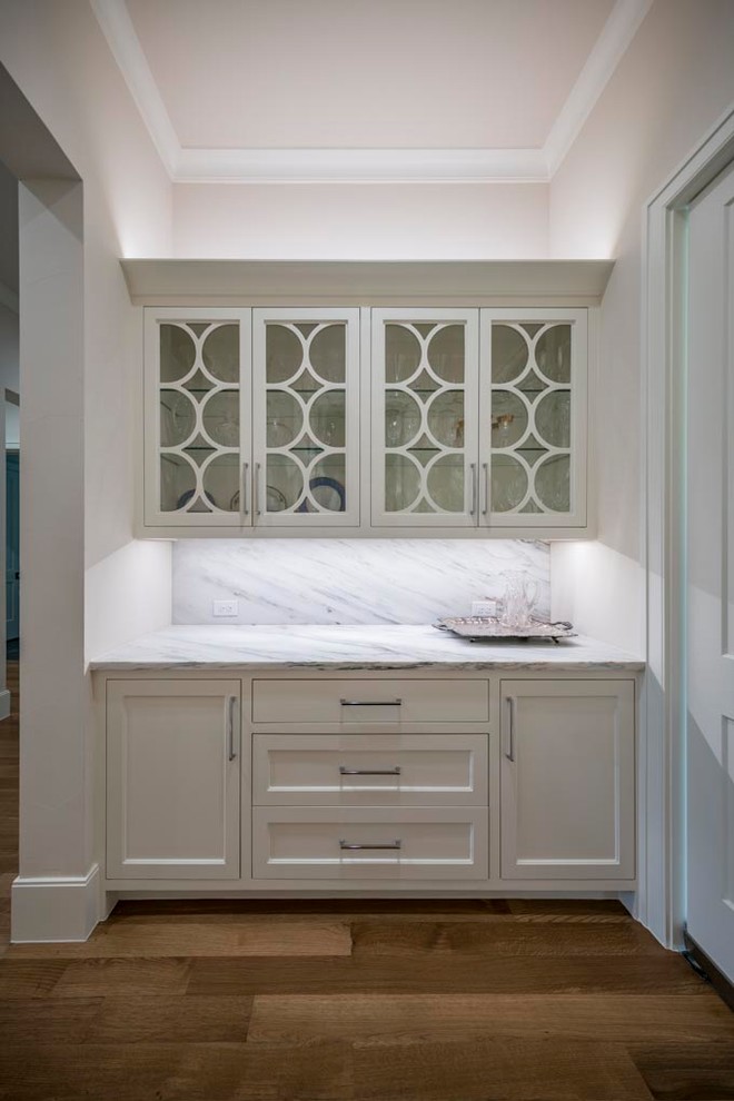 Exempel på en mellanstor klassisk u-formad hemmabar, med skåp i shakerstil, vita skåp, marmorbänkskiva, mellanmörkt trägolv och brunt golv