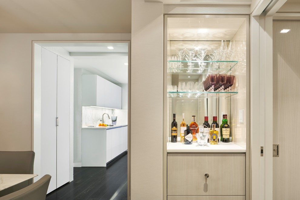 Medium sized contemporary single-wall home bar in New York with no sink, flat-panel cabinets, beige cabinets, mirror splashback, dark hardwood flooring, brown floors and white worktops.