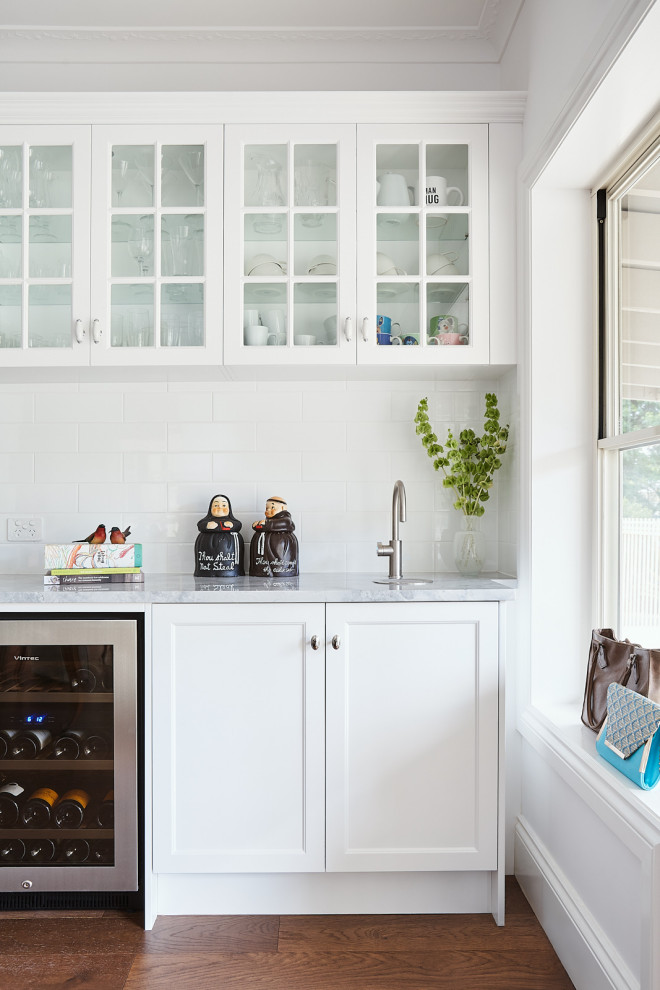 Klassische Hausbar mit Schrankfronten im Shaker-Stil, weißen Schränken, Marmor-Arbeitsplatte, Küchenrückwand in Weiß, Rückwand aus Metrofliesen und dunklem Holzboden in Brisbane