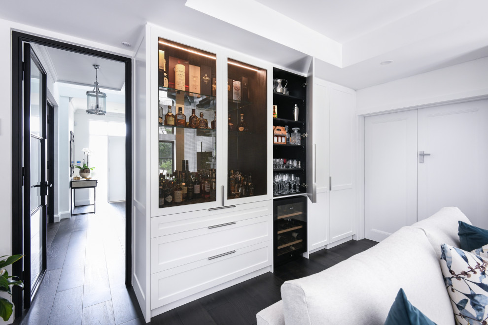 Modelo de bar en casa moderno pequeño con armarios estilo shaker, puertas de armario blancas, encimera de mármol, salpicadero con efecto espejo, suelo de madera oscura, suelo negro y encimeras negras