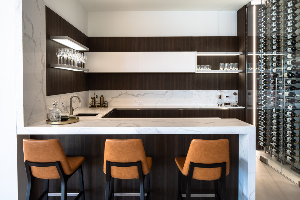 Wet bar - large contemporary u-shaped gray floor and porcelain tile wet bar idea in Miami with an undermount sink, flat-panel cabinets, marble countertops, white countertops, dark wood cabinets and white backsplash
