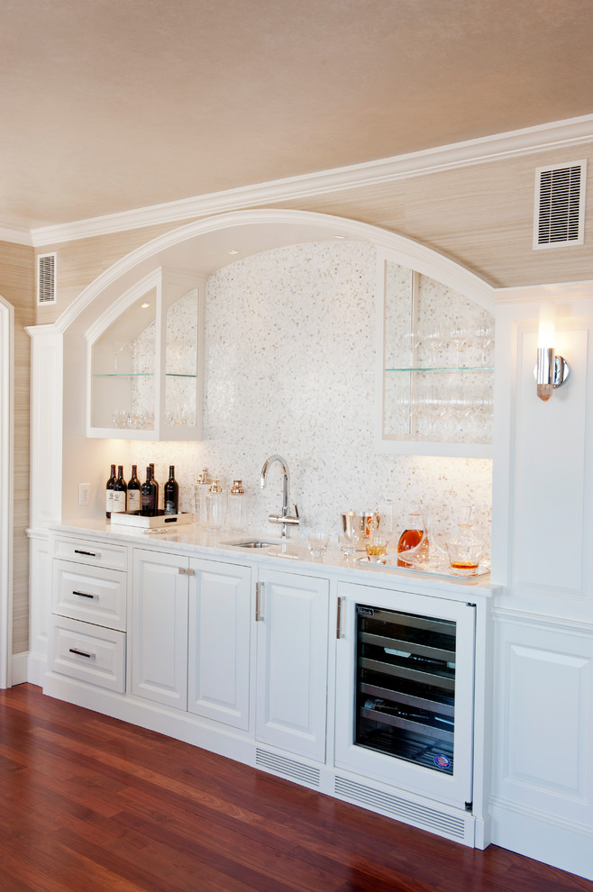 Foto på en mellanstor vintage vita linjär hemmabar med vask, med en undermonterad diskho, luckor med upphöjd panel, vita skåp, marmorbänkskiva, vitt stänkskydd, stänkskydd i mosaik, brunt golv och mörkt trägolv