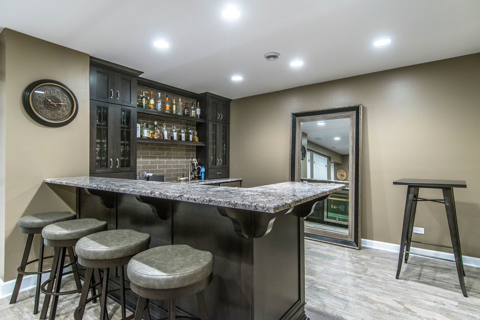 Inspiration for a contemporary l-shaped wet bar in Chicago with a built-in sink, shaker cabinets, black cabinets, granite worktops, grey splashback, light hardwood flooring, grey floors and grey worktops.