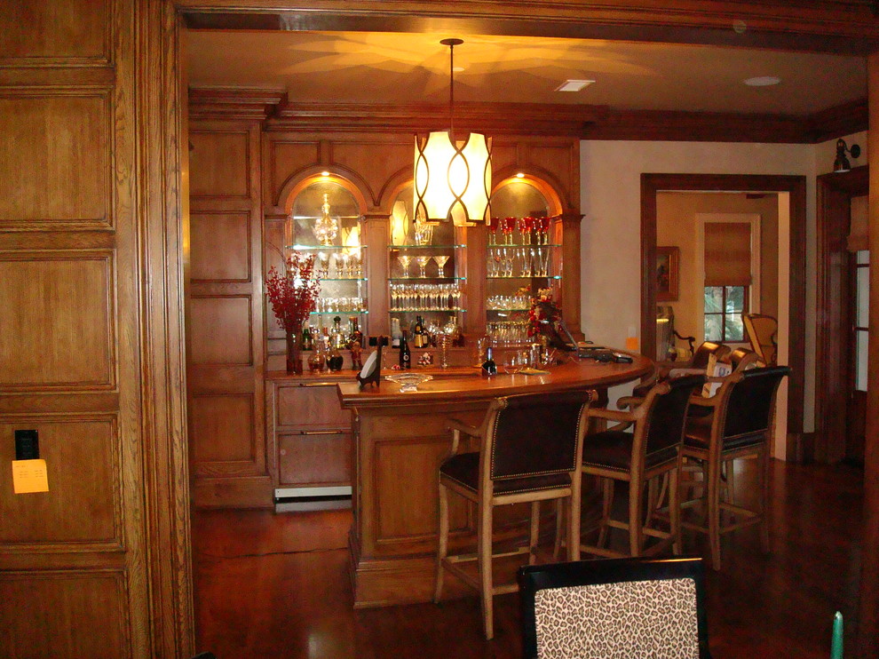 Example of a large classic u-shaped dark wood floor seated home bar design in Other with medium tone wood cabinets and wood countertops