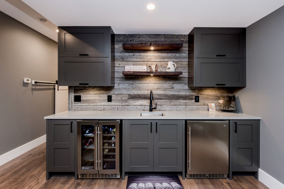 Medium sized traditional single-wall wet bar in Other with a submerged sink, shaker cabinets, grey cabinets, quartz worktops, brown splashback, wood splashback and grey worktops.