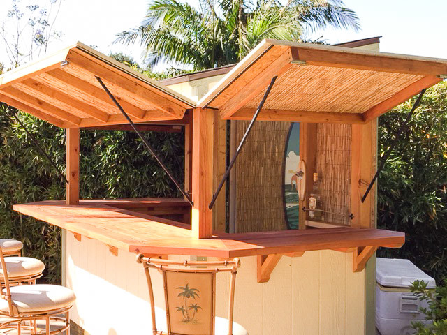 Immagine di un piccolo bancone bar tropicale con top in legno, paraspruzzi marrone, paraspruzzi in legno, pavimento in cemento e pavimento grigio