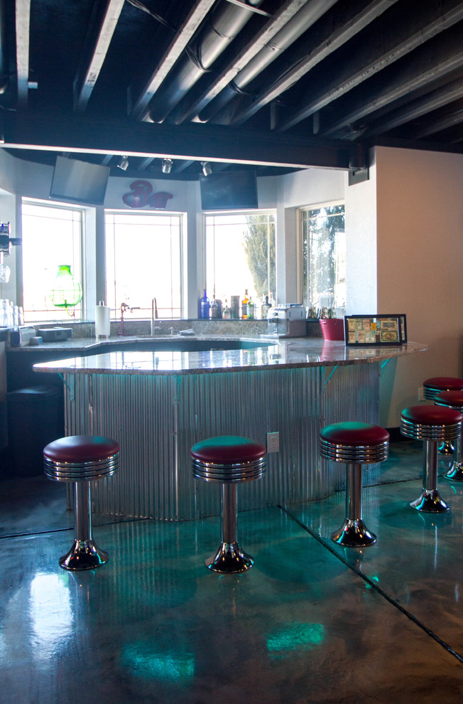 Immagine di un angolo bar con lavandino moderno di medie dimensioni con lavello sottopiano, ante lisce, ante nere, top in granito, paraspruzzi grigio, paraspruzzi in lastra di pietra e pavimento in cemento