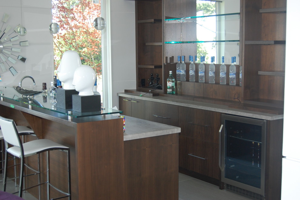 Cette image montre un grand bar de salon linéaire minimaliste en bois brun avec des tabourets, un placard à porte plane, un plan de travail beige et une crédence miroir.