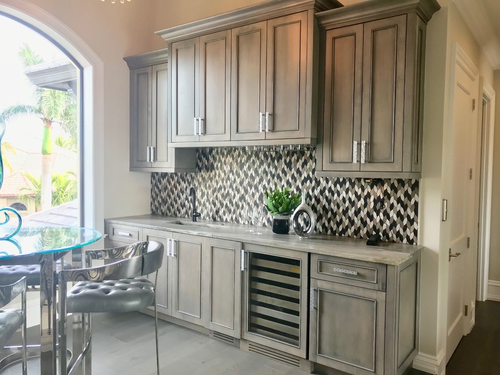 Inspiration for a large contemporary single-wall dark wood floor and brown floor wet bar remodel in Other with recessed-panel cabinets, gray cabinets, marble countertops, multicolored backsplash and mosaic tile backsplash