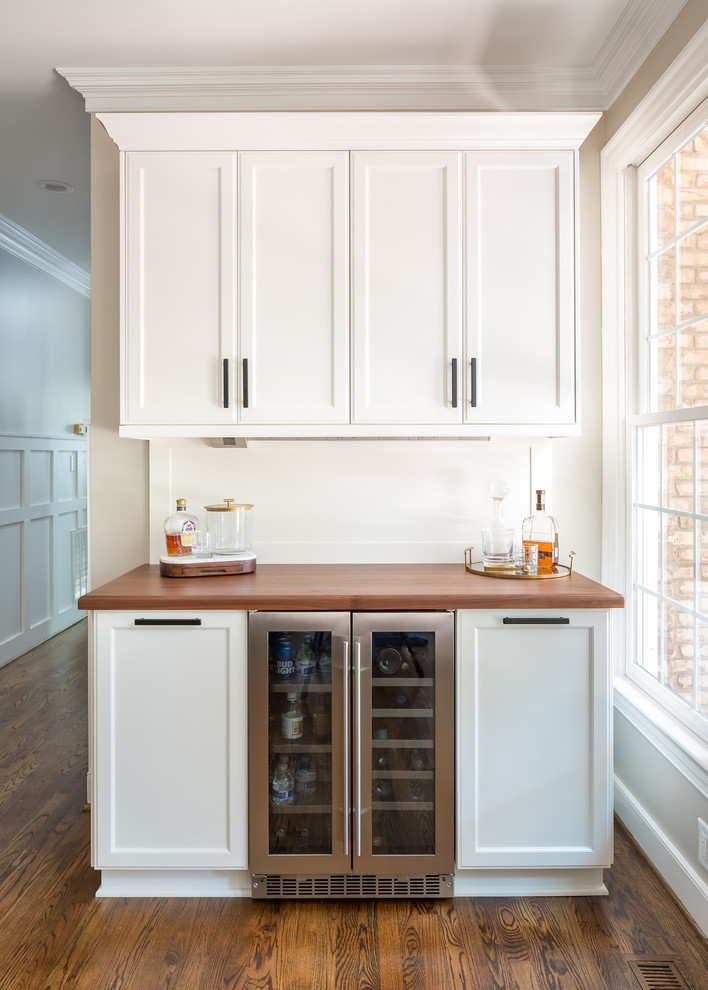 Inspiration for a transitional medium tone wood floor home bar remodel in Raleigh with shaker cabinets, white cabinets and wood countertops