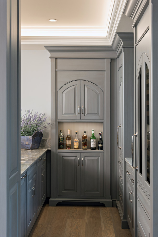 Photo of a large bohemian l-shaped breakfast bar in Boston with raised-panel cabinets, grey cabinets, marble worktops, grey splashback, light hardwood flooring and brown floors.