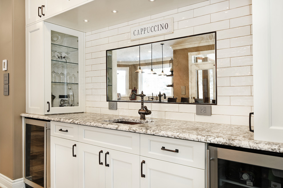 Inspiration for a large transitional single-wall wet bar remodel in Toronto with an undermount sink, shaker cabinets, white cabinets, granite countertops, white backsplash and subway tile backsplash