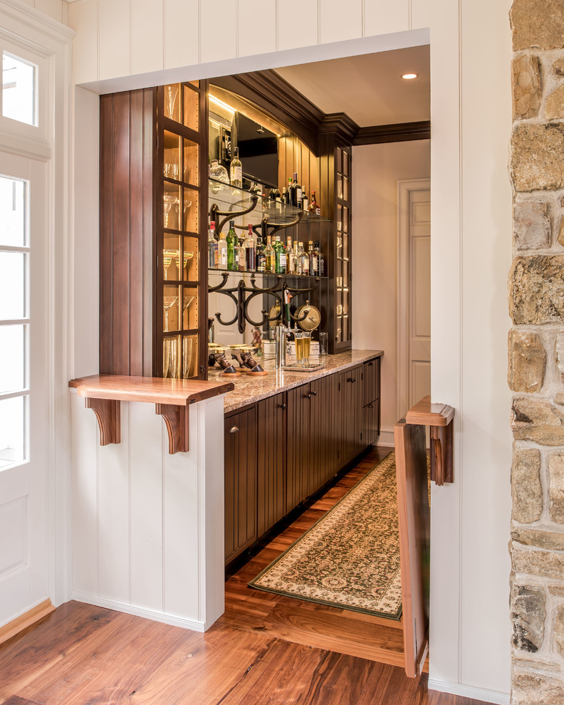 Foto de bar en casa tradicional con armarios tipo vitrina, puertas de armario de madera en tonos medios, encimera de madera y salpicadero con efecto espejo
