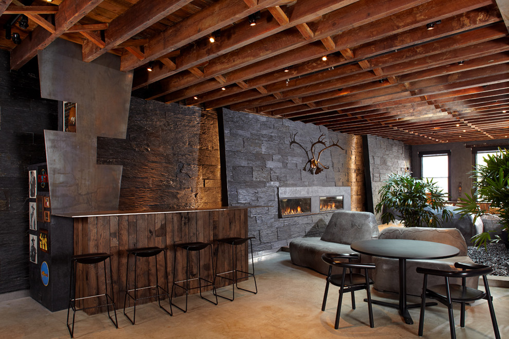 Ispirazione per un bancone bar minimalista di medie dimensioni con paraspruzzi nero, paraspruzzi con piastrelle in pietra e pavimento in cemento