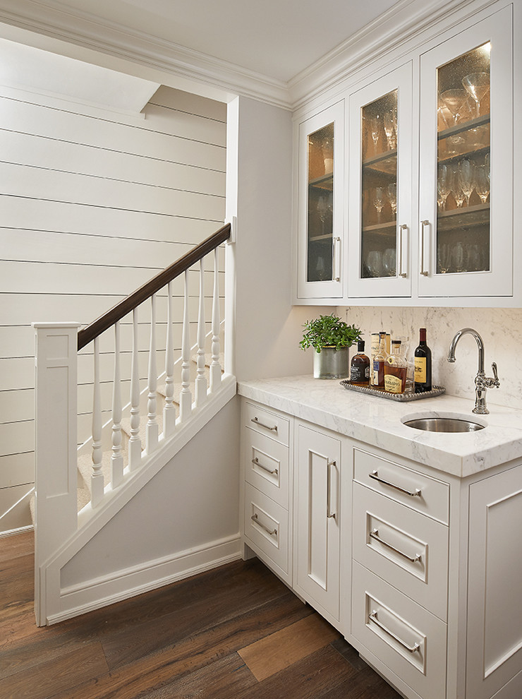 Inspiration för en liten vintage vita linjär vitt hemmabar med vask, med en undermonterad diskho, vita skåp, marmorbänkskiva, vitt stänkskydd, stänkskydd i marmor, mellanmörkt trägolv och luckor med glaspanel