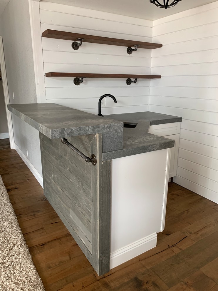 This is an example of a small industrial l-shaped wet bar in Sacramento with a submerged sink, engineered stone countertops, dark hardwood flooring, brown floors and grey worktops.