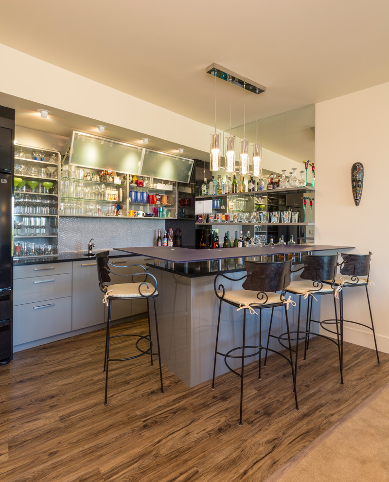 Diseño de bar en casa con barra de bar de galera moderno con armarios tipo vitrina, puertas de armario grises, encimera de cuarzo compacto y salpicadero con mosaicos de azulejos