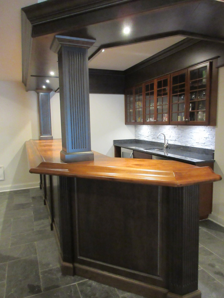 Inspiration for a medium sized traditional galley wet bar in DC Metro with raised-panel cabinets, dark wood cabinets, wood worktops and stone tiled splashback.