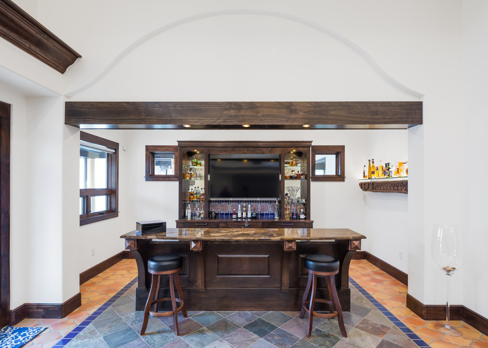 Example of a tuscan galley multicolored floor home bar design in Austin with dark wood cabinets and brown countertops