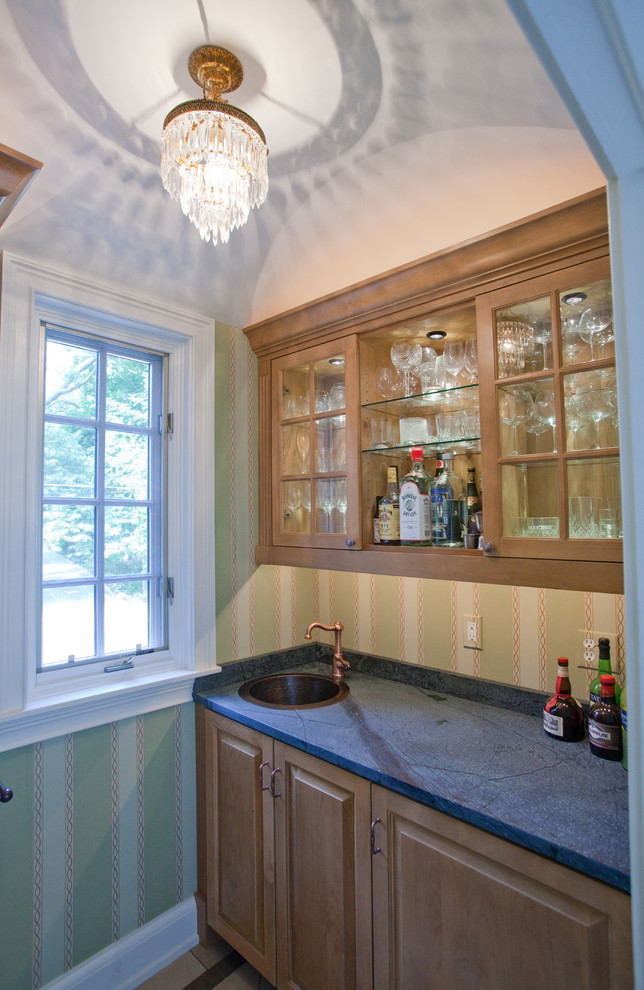 This is an example of a small traditional wet bar in Other with a built-in sink, medium wood cabinets, soapstone worktops, green splashback and ceramic flooring.