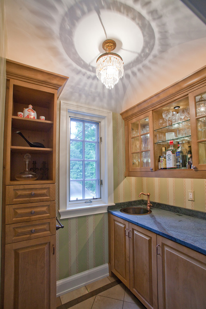 Example of a small classic ceramic tile wet bar design in Other with a drop-in sink, medium tone wood cabinets, soapstone countertops and green backsplash