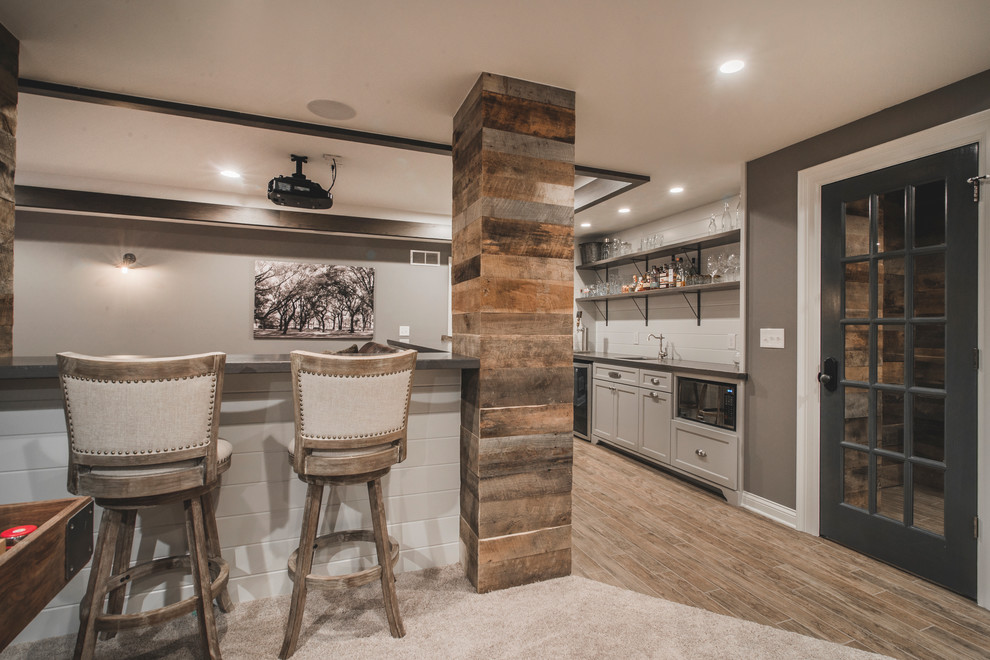 Large rustic single-wall wet bar in Columbus with a submerged sink, shaker cabinets, grey cabinets, wood worktops, grey splashback and ceramic flooring.