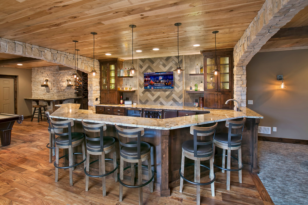 Rustikale Hausbar in U-Form mit profilierten Schrankfronten, dunklen Holzschränken, Küchenrückwand in Grau und braunem Holzboden in Minneapolis