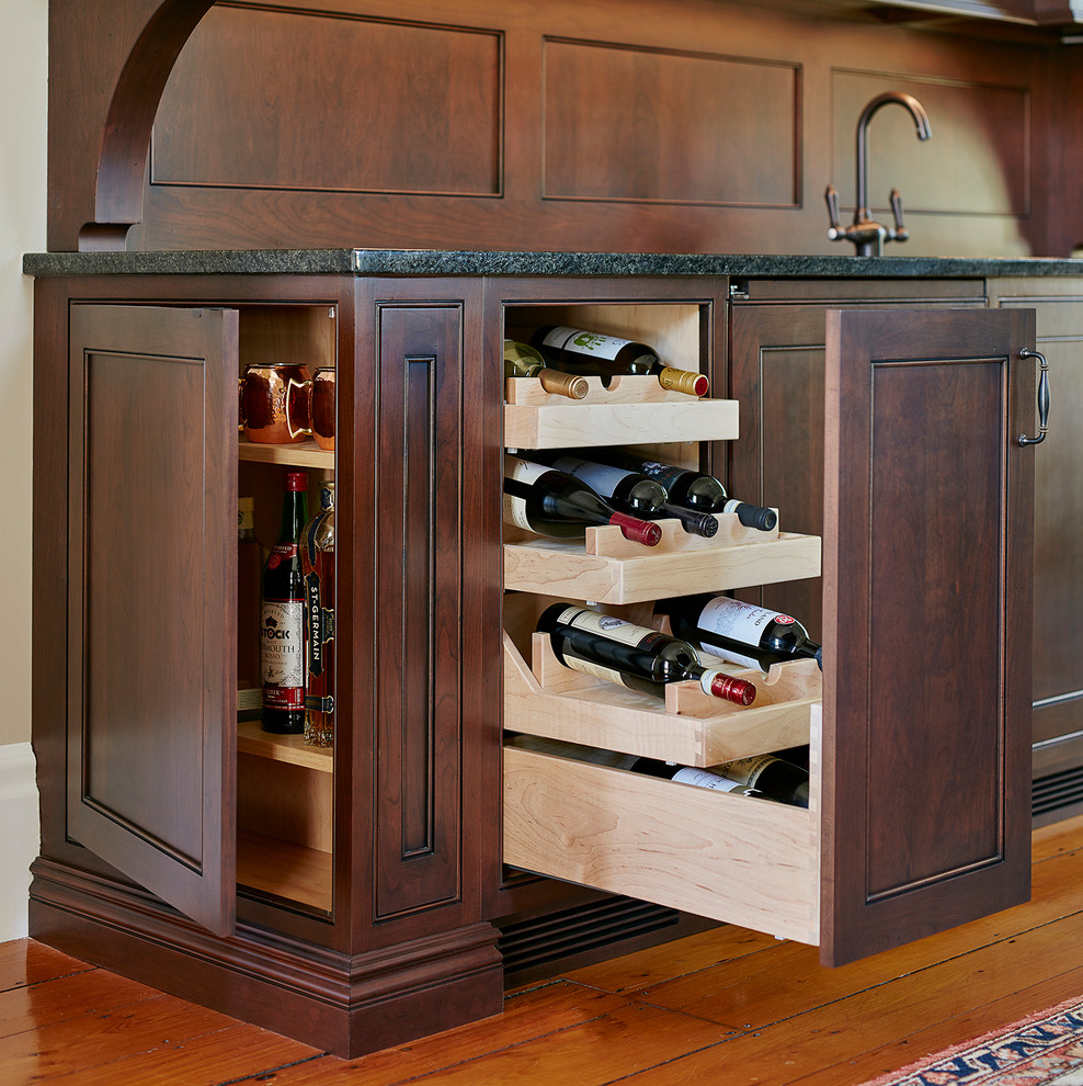 Wet bar - mid-sized traditional single-wall medium tone wood floor and brown floor wet bar idea in Boston with an undermount sink, recessed-panel cabinets, dark wood cabinets, granite countertops and black countertops