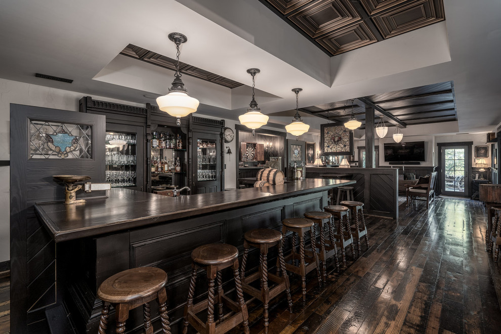 Foto di un grande bancone bar country con ante di vetro, ante nere, top in legno, paraspruzzi a specchio, parquet scuro, pavimento marrone e top marrone