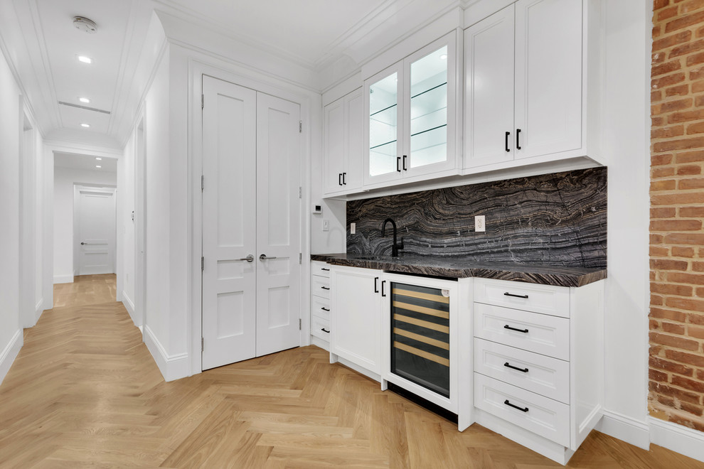 Exempel på en liten modern svarta parallell svart hemmabar med vask, med en undermonterad diskho, skåp i shakerstil, vita skåp, marmorbänkskiva, svart stänkskydd, stänkskydd i marmor, mellanmörkt trägolv och brunt golv