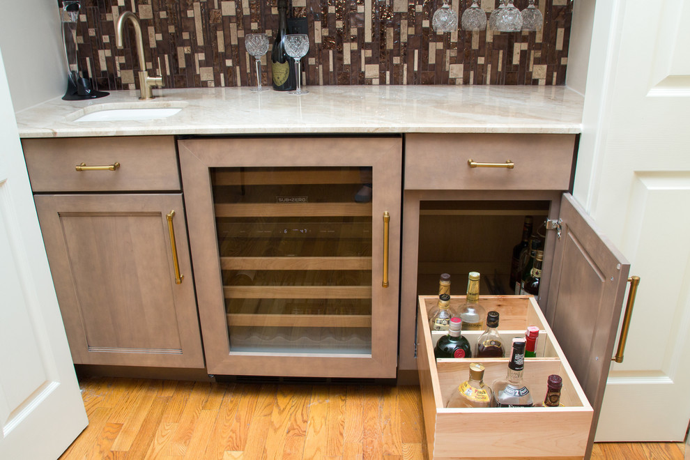 Bild på en liten funkis linjär hemmabar med vask, med en undermonterad diskho, skåp i shakerstil, beige skåp, marmorbänkskiva, brunt stänkskydd, stänkskydd i glaskakel, ljust trägolv och brunt golv