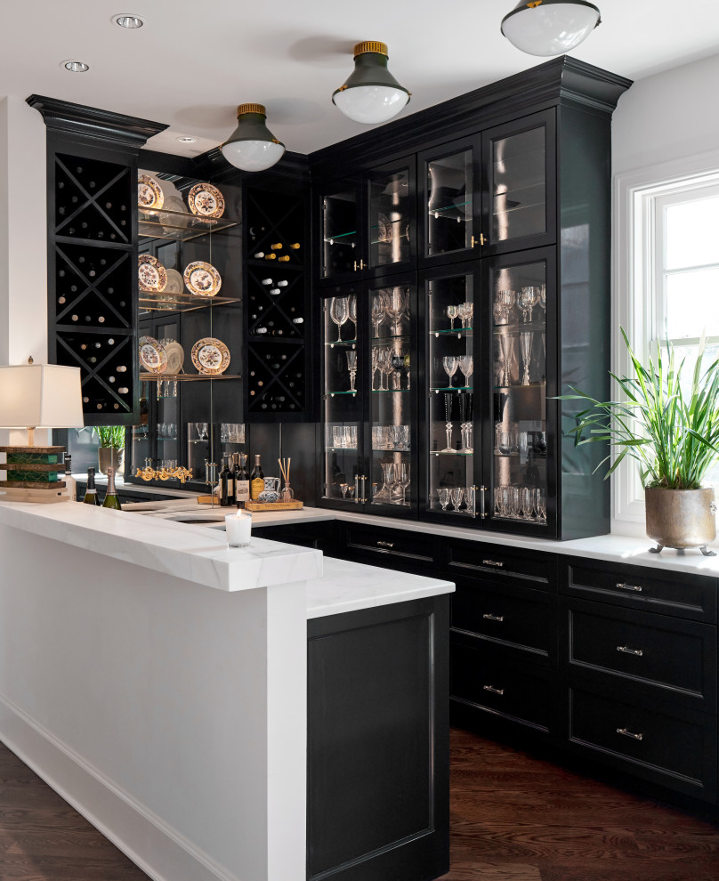 Inspiration for a large traditional home bar in Austin with a submerged sink, recessed-panel cabinets, black cabinets, marble worktops, mirror splashback, medium hardwood flooring, brown floors and white worktops.