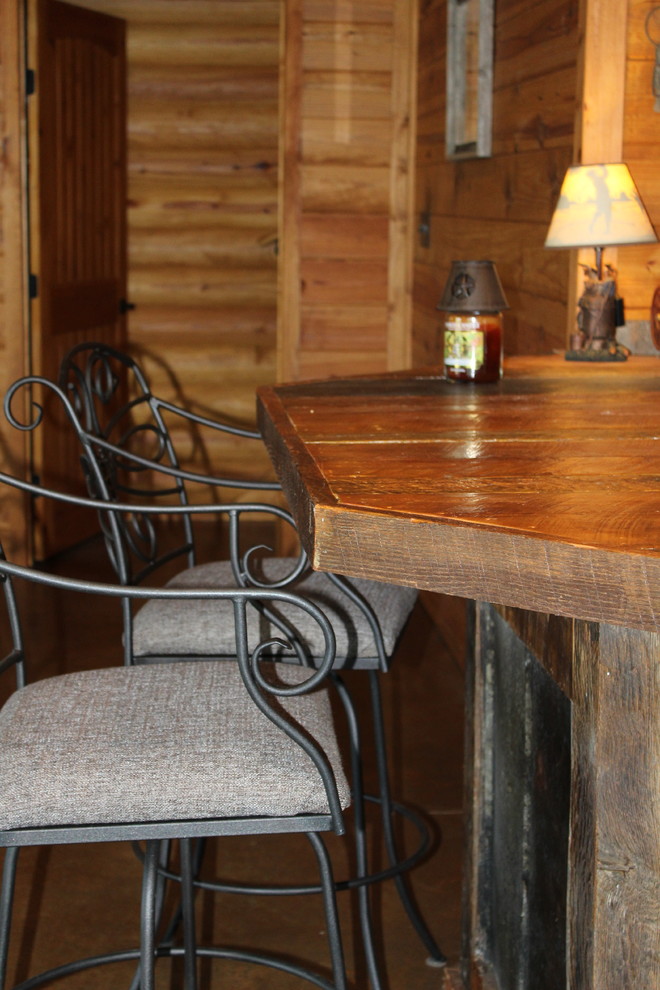 アトランタにある小さなラスティックスタイルのおしゃれな着席型バー (コの字型、ヴィンテージ仕上げキャビネット、木材カウンター、コンクリートの床、茶色い床、茶色いキッチンカウンター、シンクなし) の写真