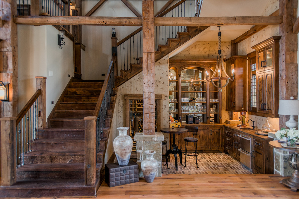 This is an example of a rustic l-shaped home bar in Houston with a submerged sink, dark wood cabinets and brick flooring.