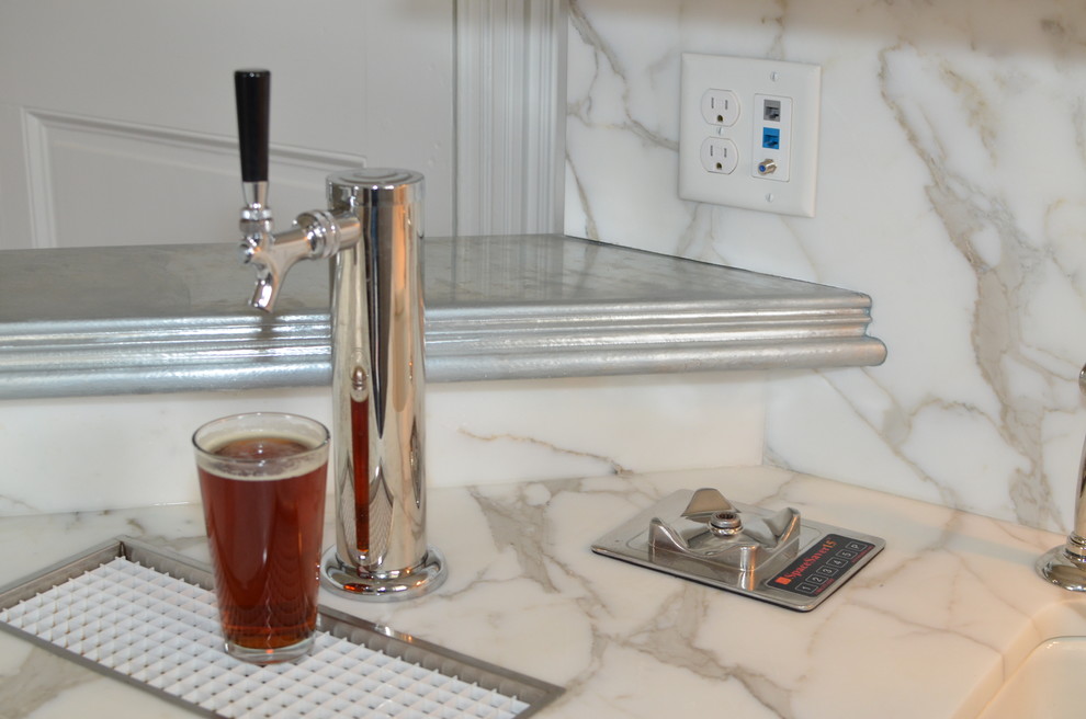 Mid-sized transitional l-shaped wet bar photo in Baltimore with an undermount sink, shaker cabinets, white cabinets, marble countertops, white backsplash and stone slab backsplash