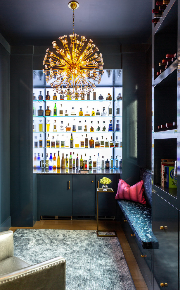 Cette image montre un bar de salon avec évier design en L avec un évier encastré, un placard à porte plane, des portes de placard bleues, un sol en bois brun, un sol marron et un plan de travail gris.