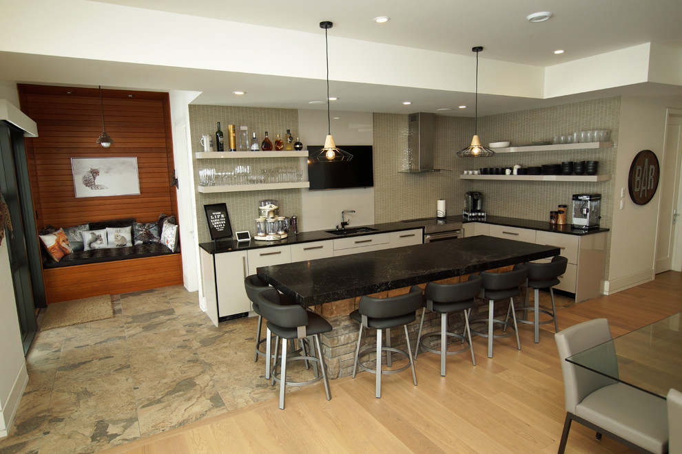 Large minimalist l-shaped seated home bar photo in Other with an undermount sink, flat-panel cabinets, gray cabinets, quartz countertops, gray backsplash, stone slab backsplash and black countertops