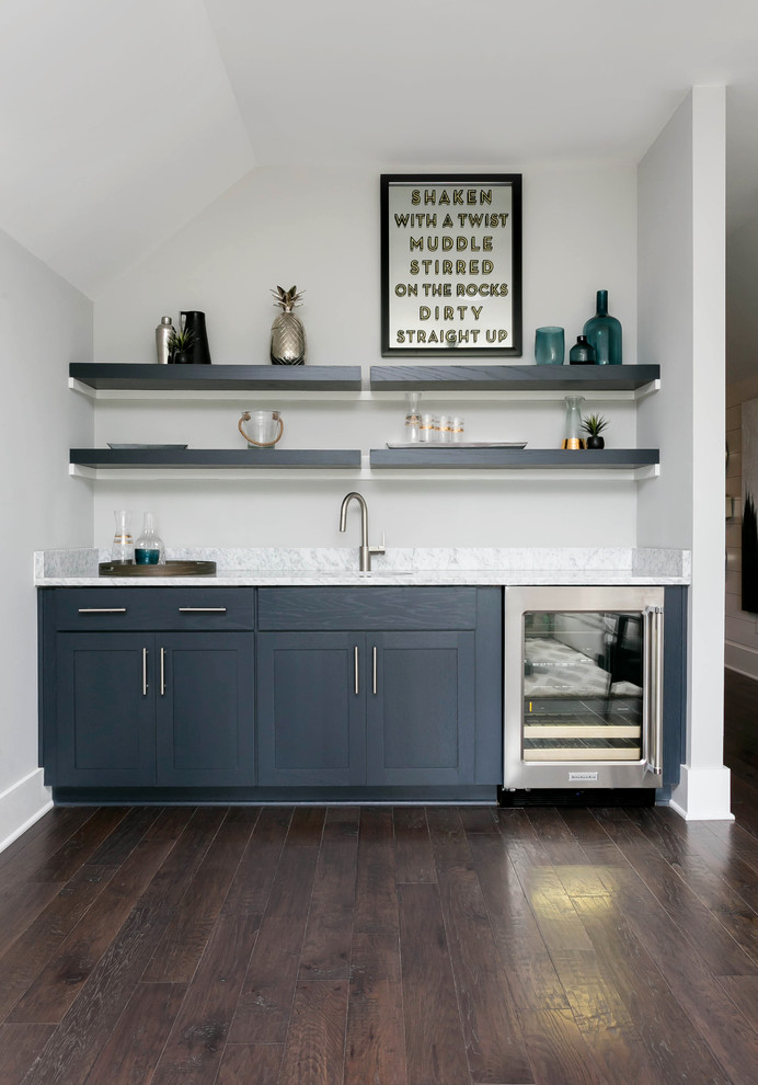 Inredning av en mellanstor grå linjär grått hemmabar med vask, med en undermonterad diskho, skåp i shakerstil, blå skåp, marmorbänkskiva, mellanmörkt trägolv och brunt golv