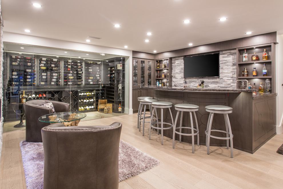 Diseño de bar en casa con barra de bar lineal tradicional grande con armarios con paneles lisos, puertas de armario marrones, suelo de madera en tonos medios y suelo gris