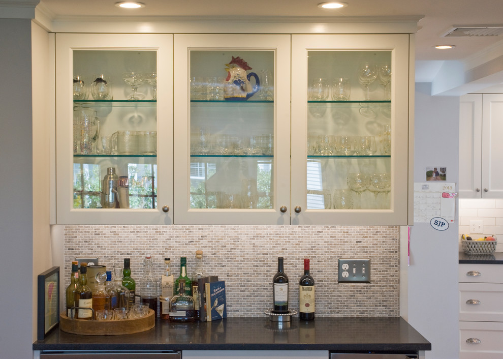 Photo of a classic home bar in Boston with glass-front cabinets, white cabinets, granite worktops, multi-coloured splashback, mosaic tiled splashback and black worktops.