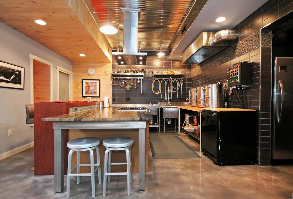 Inredning av ett modernt mellanstort l-kök, med granitbänkskiva, flerfärgad stänkskydd, rostfria vitvaror, betonggolv, en köksö och brunt golv