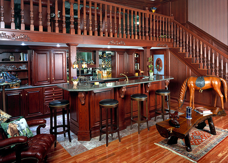 Réalisation d'un grand bar de salon parallèle tradition en bois brun avec des tabourets, un placard avec porte à panneau surélevé et un plan de travail en granite.