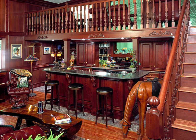 Modelo de bar en casa con barra de bar de galera tradicional grande con armarios con paneles con relieve, puertas de armario de madera oscura y encimera de granito