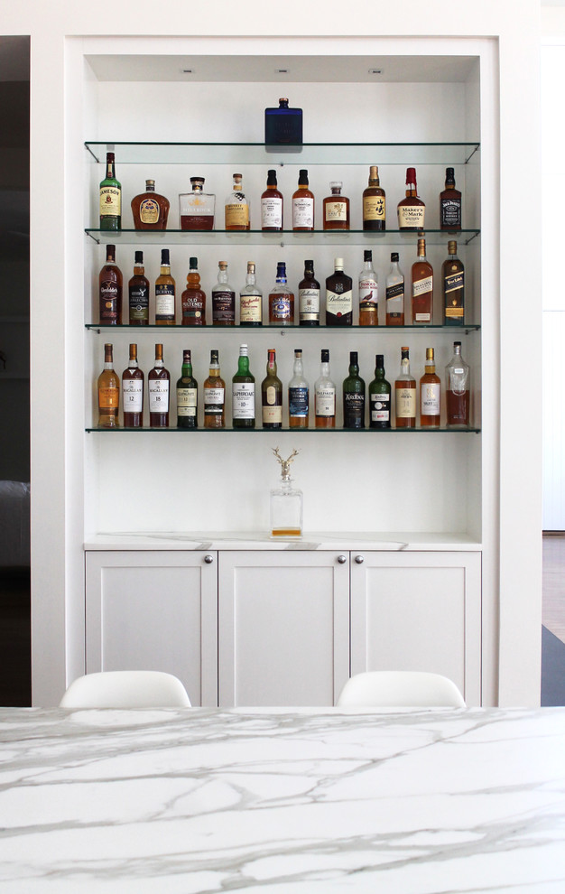 Home bar - transitional home bar idea in New York with white cabinets, marble countertops, white backsplash, subway tile backsplash and shaker cabinets