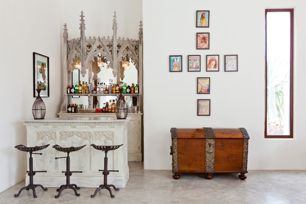 Inspiration for a mid-sized eclectic galley concrete floor seated home bar remodel in London with white cabinets, mirror backsplash, open cabinets, marble countertops and no sink